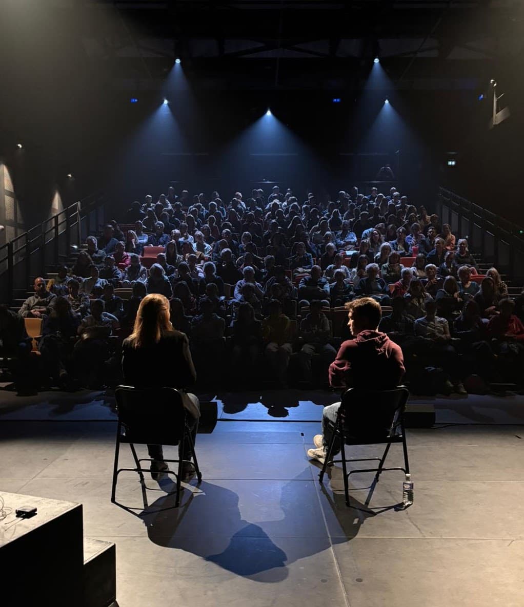 Deux comédiens assis face à une salle comble, pendant l’échange qui suit la représentation